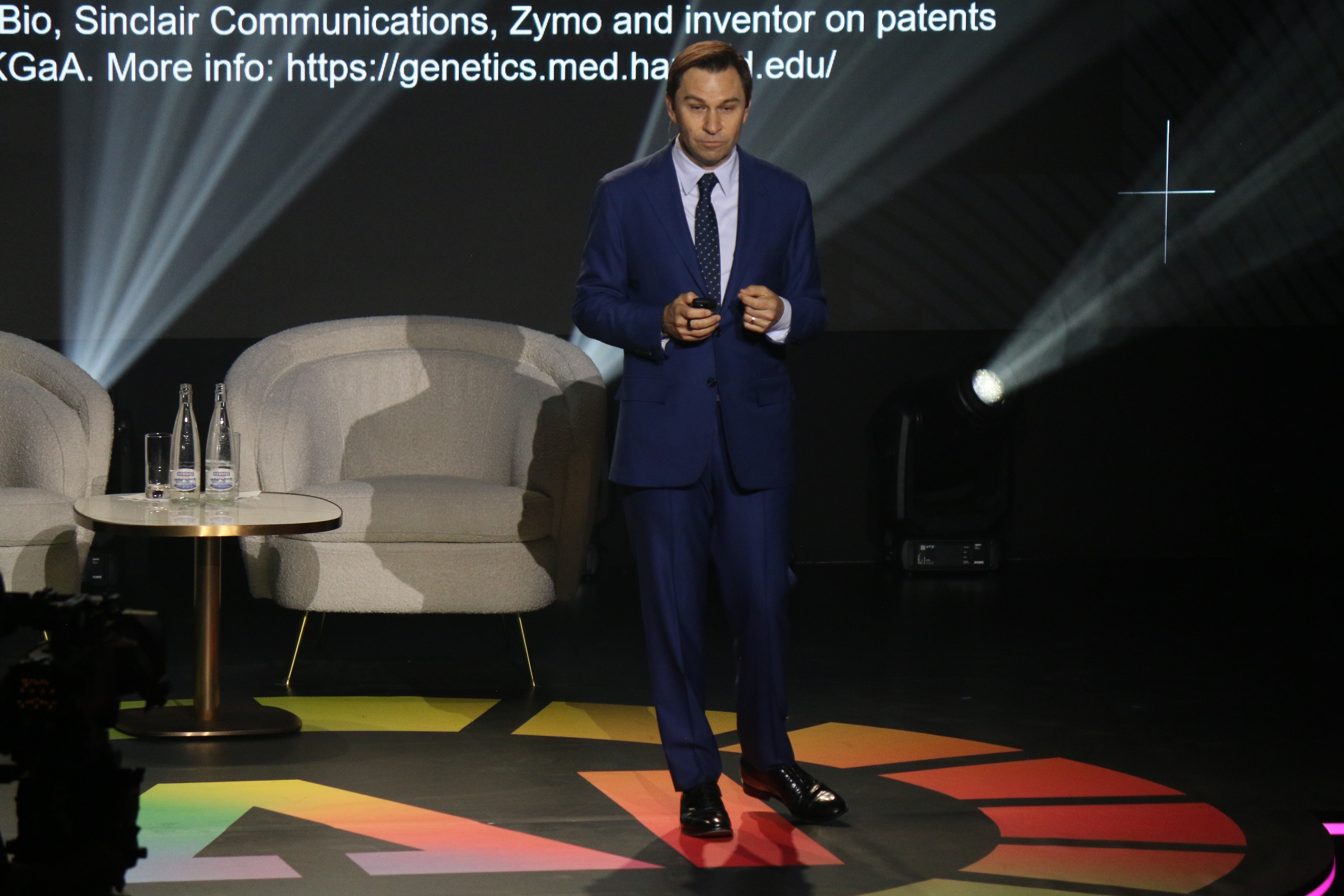 David Sinclair in a blue suit speaking onstage at the 2025 AI for Good Summit
